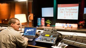 Un homme travaille à un bureau équipé de matériel audio, d’un ordinateur portable et d’un écran de présentation affichant le texte « Les Trophées de l’Artisanat 2009 ».