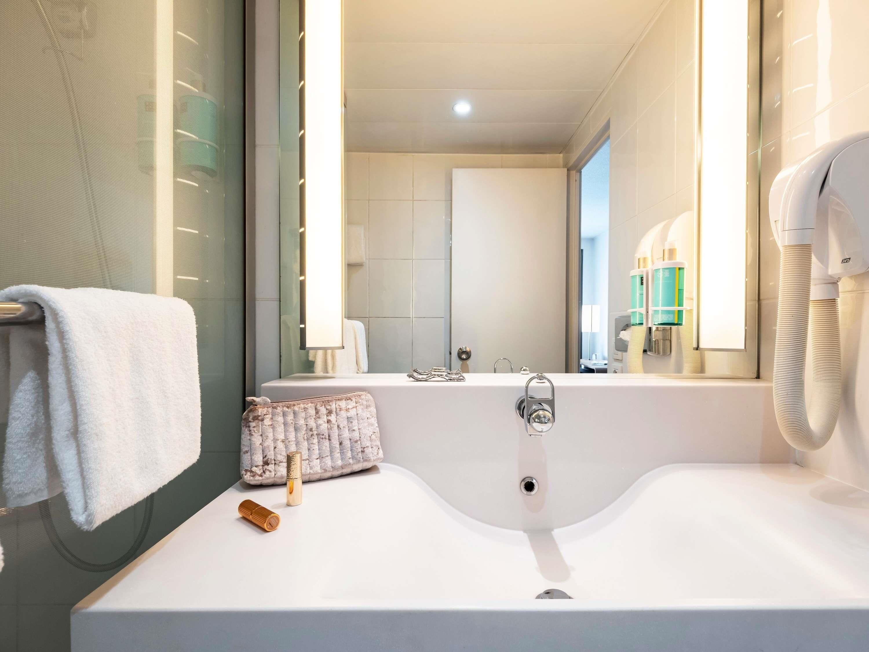 Un baño moderno con una bañera grande, un tocador con espejo y un perchero para toallas.