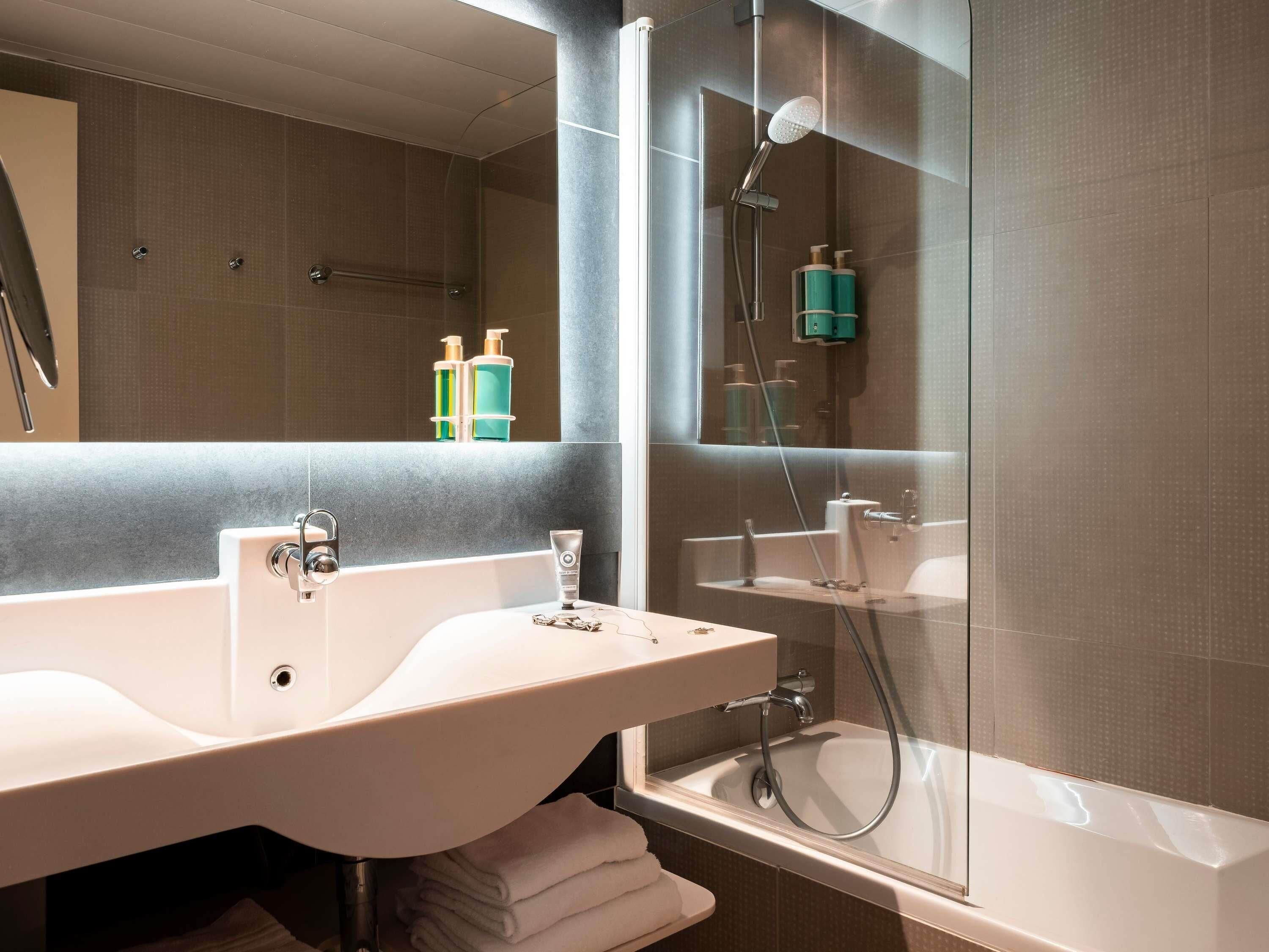 Un baño moderno con un lavamanos grande, espejo y ducha con mampara de vidrio.