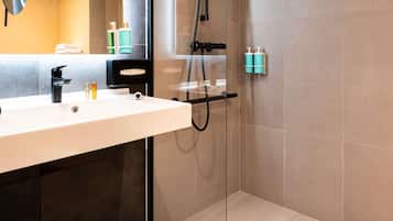 A modern bathroom with a white sink, black faucet, and a glass shower enclosure.