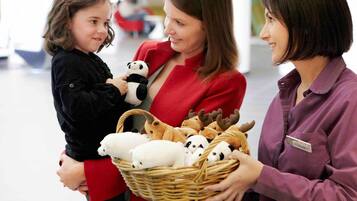 Three people holding a basket with stuffed animals.