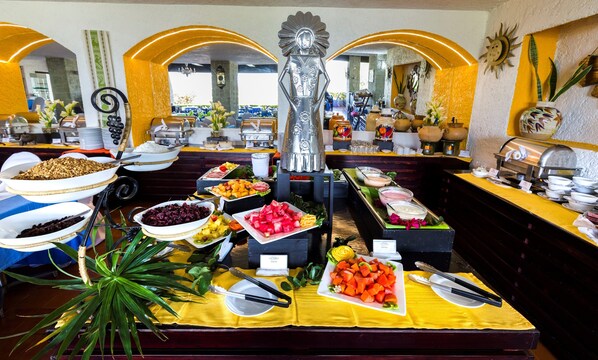 Montaje de bufé con diferentes alimentos y una estatua decorativa.