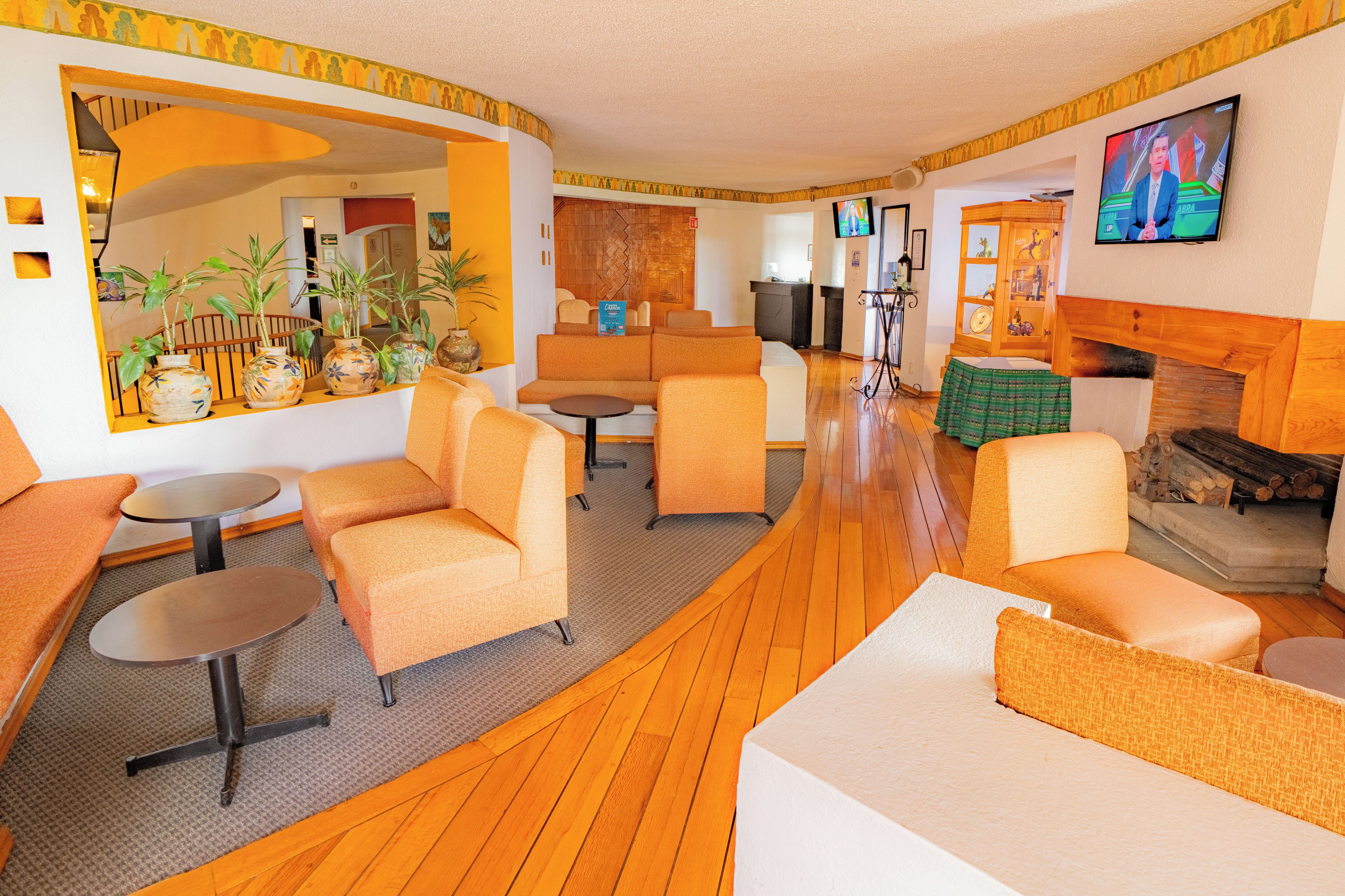 Un hall d’hôtel doté d’espaces aménagés avec des sièges, d’une cheminée et d’un téléviseur.