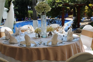 A round table set for a formal event with a beige tablecloth, white napkins, and silverware.