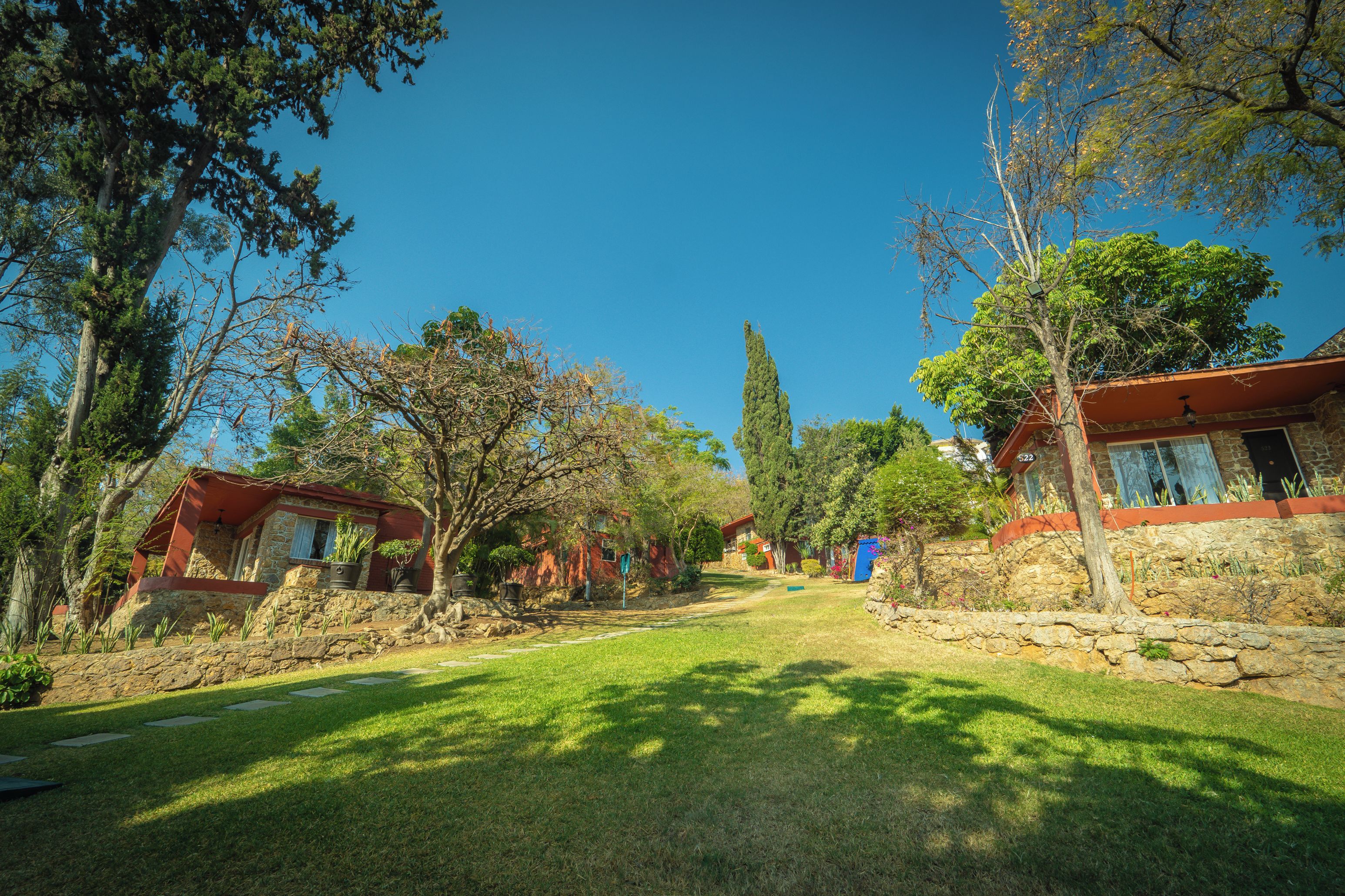 A residential area with stone houses, a clear sky, and a well-maintained lawn.