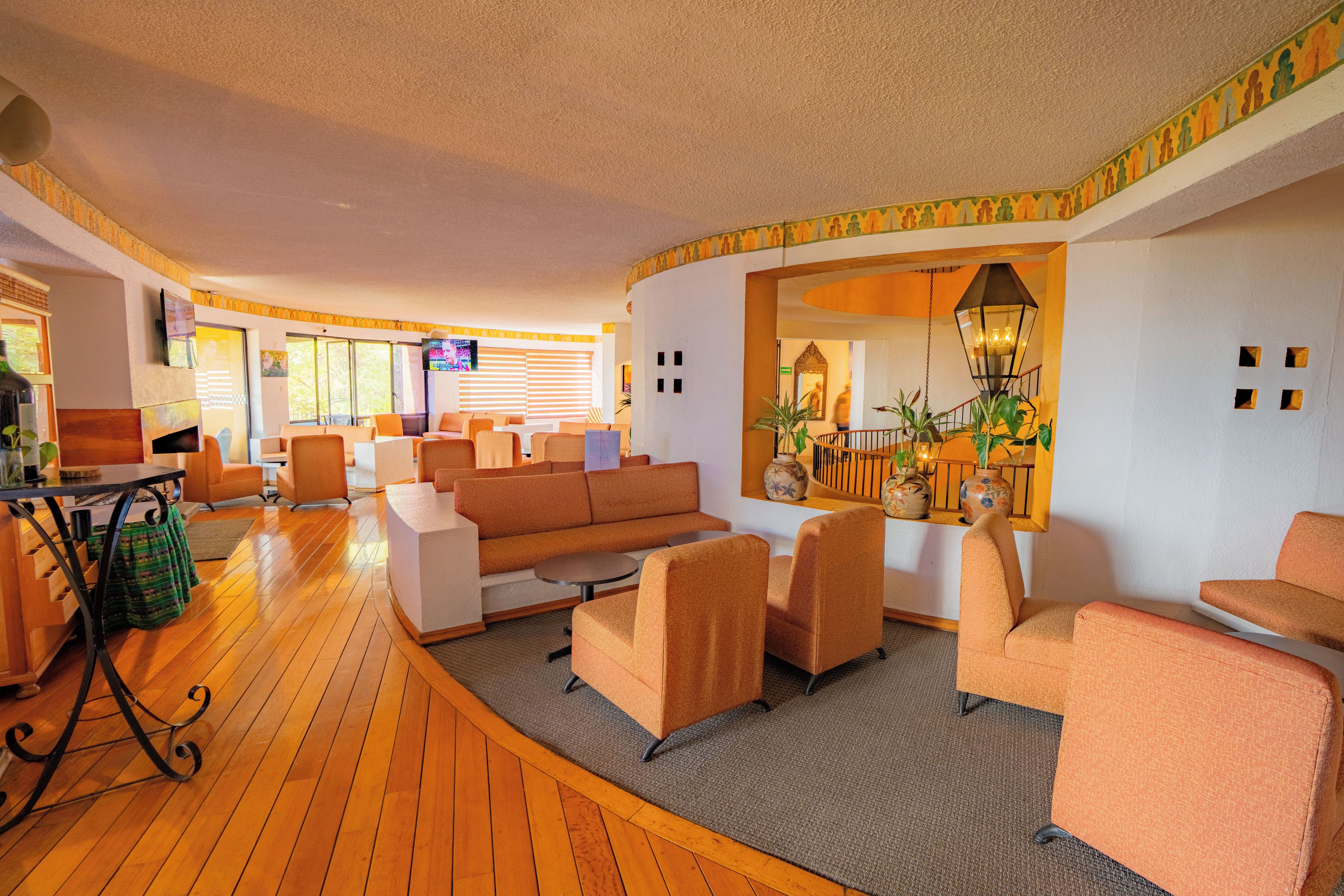 A hotel lobby with a curved wooden floor, sofas, and armchairs arranged for seating.