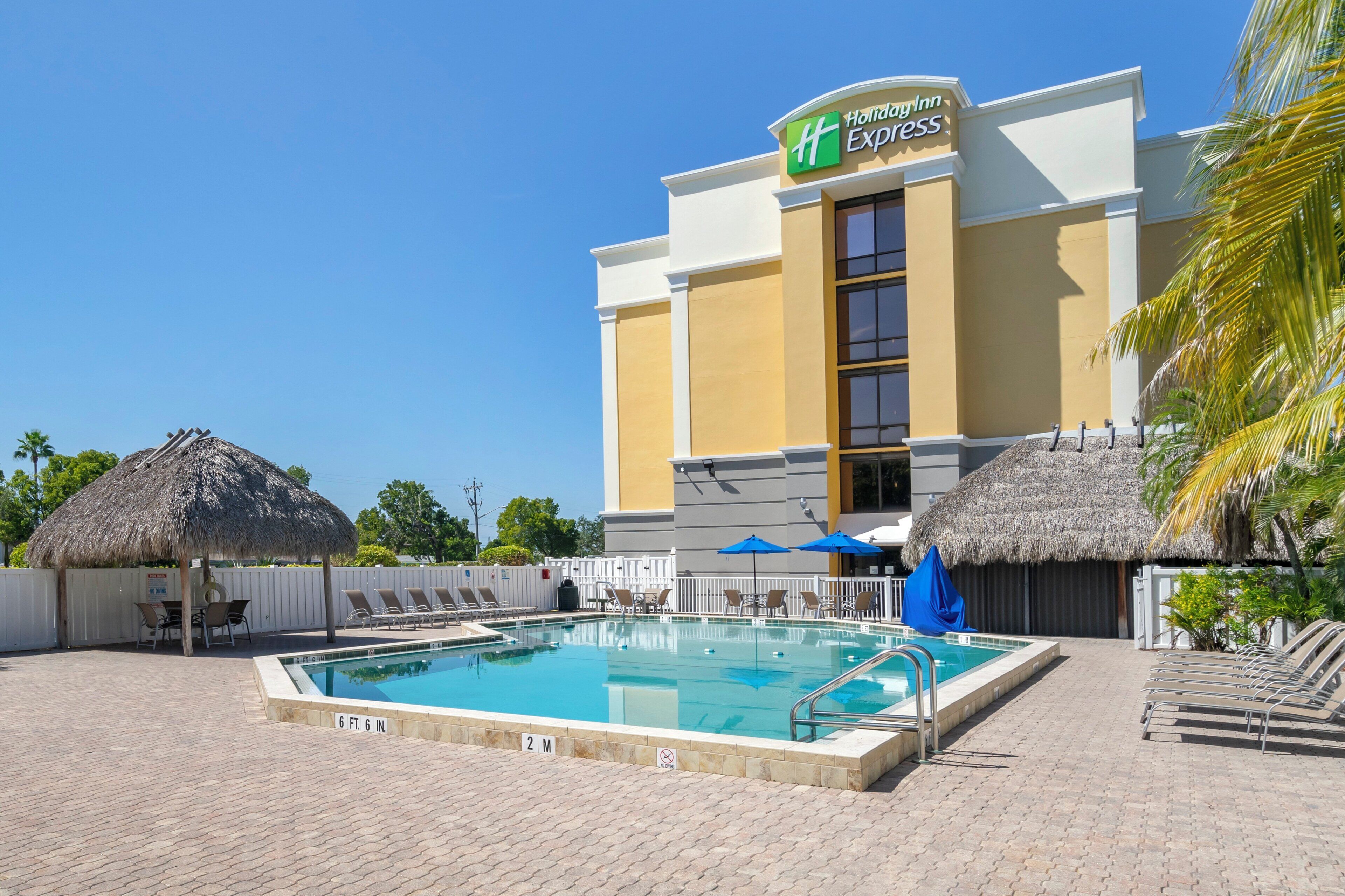 A Holiday Inn Express hotel with a pool area, including lounge chairs and umbrellas.