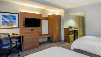 Habitación de hotel con escritorio, silla, televisión, armario y cama.