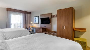 Habitación de hotel con dos camas, un escritorio, televisión de pantalla plana, una silla y un armario.