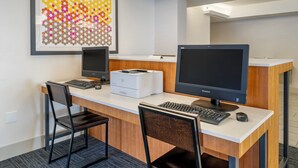 A modern office space with two desks, each equipped with a computer monitor, keyboard, and mouse. There is a framed artwork on the wall above the desks. - Holiday Inn Express Cape Coral-Fort Myers Area by IHG (Cape Coral)