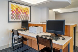 Un espacio de oficina moderno con dos escritorios, cada uno equipado con un monitor de computadora, teclado y ratón. Hay una obra de arte enmarcada en la pared sobre los escritorios.