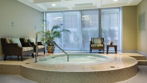 A spa area with a hot tub, two sofas, a potted plant, and a small table with a vase.