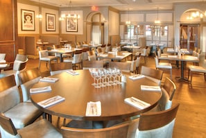 Un vaste espace dédié à la salle à manger, avec plusieurs tables rondes disposées pour accueillir les convives, entourées de chaises rembourrées.