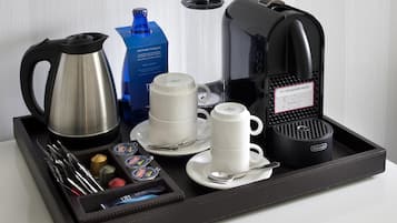 A tray with a coffee maker, a kettle, two cups, a mug, and a box of coffee pods.