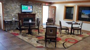 A dining area with a fireplace, stone wall, and two TVs. - Econo Lodge Cedar Rapids South (Cedar Rapids)