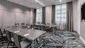 Un salón de conferencias con una larga mesa, sillas y piso alfombrado.