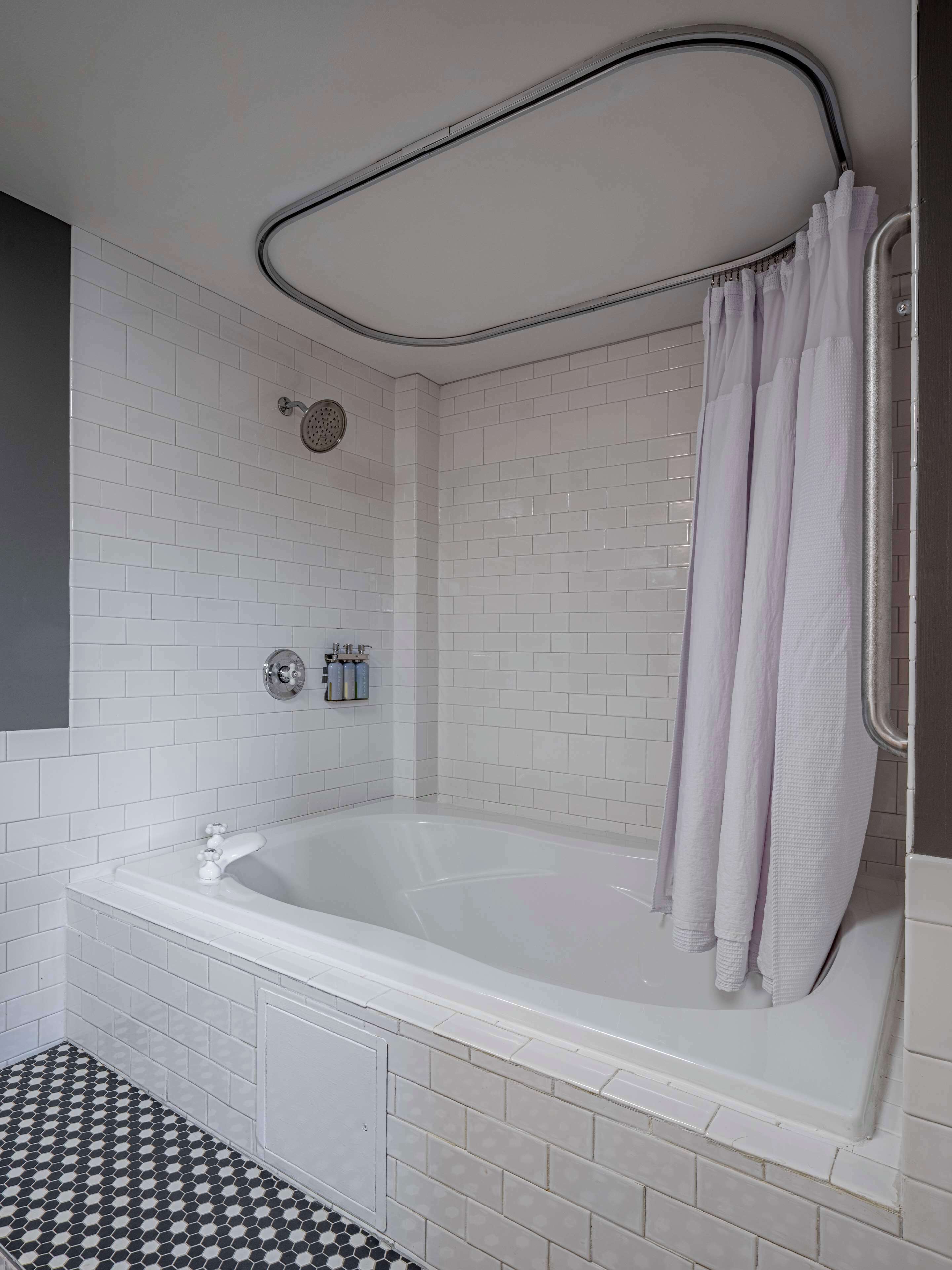A modern bathroom with a freestanding bathtub, a showerhead, and a towel rack.