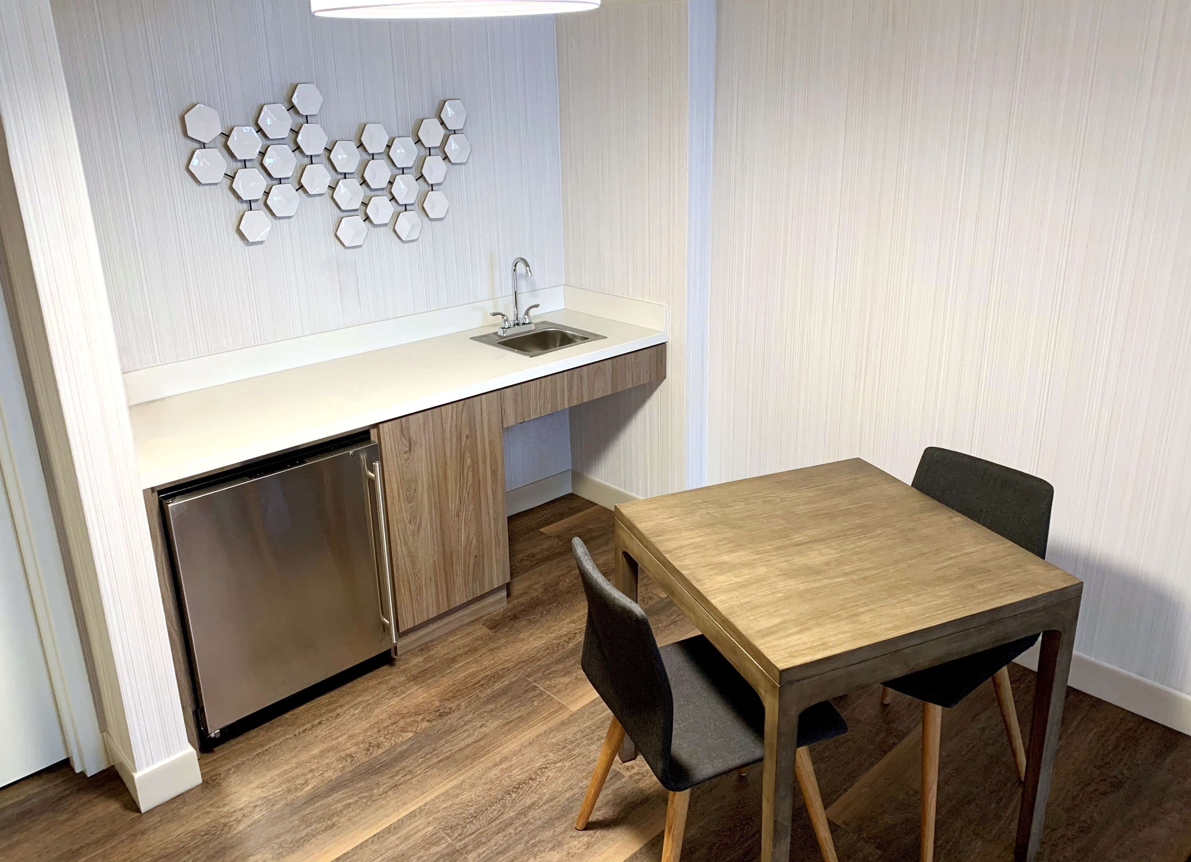 A compact kitchen with a built-in dishwasher, a sink, and a wooden dining table with chairs.