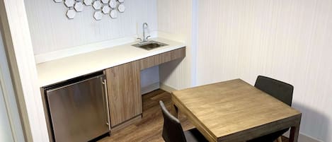 A compact kitchen with a built-in dishwasher, a sink, and a wooden dining table with chairs.