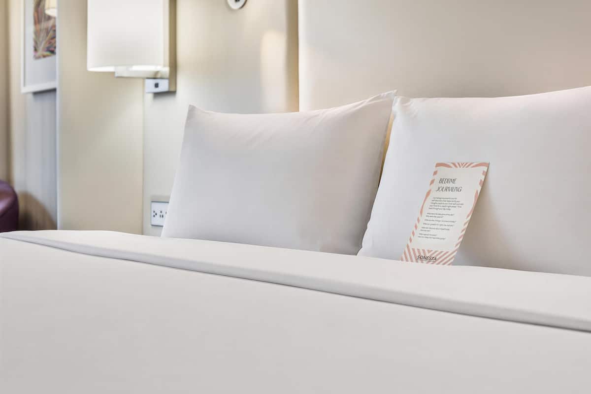 Cama com roupa de cama branca e travesseiro com etiqueta.