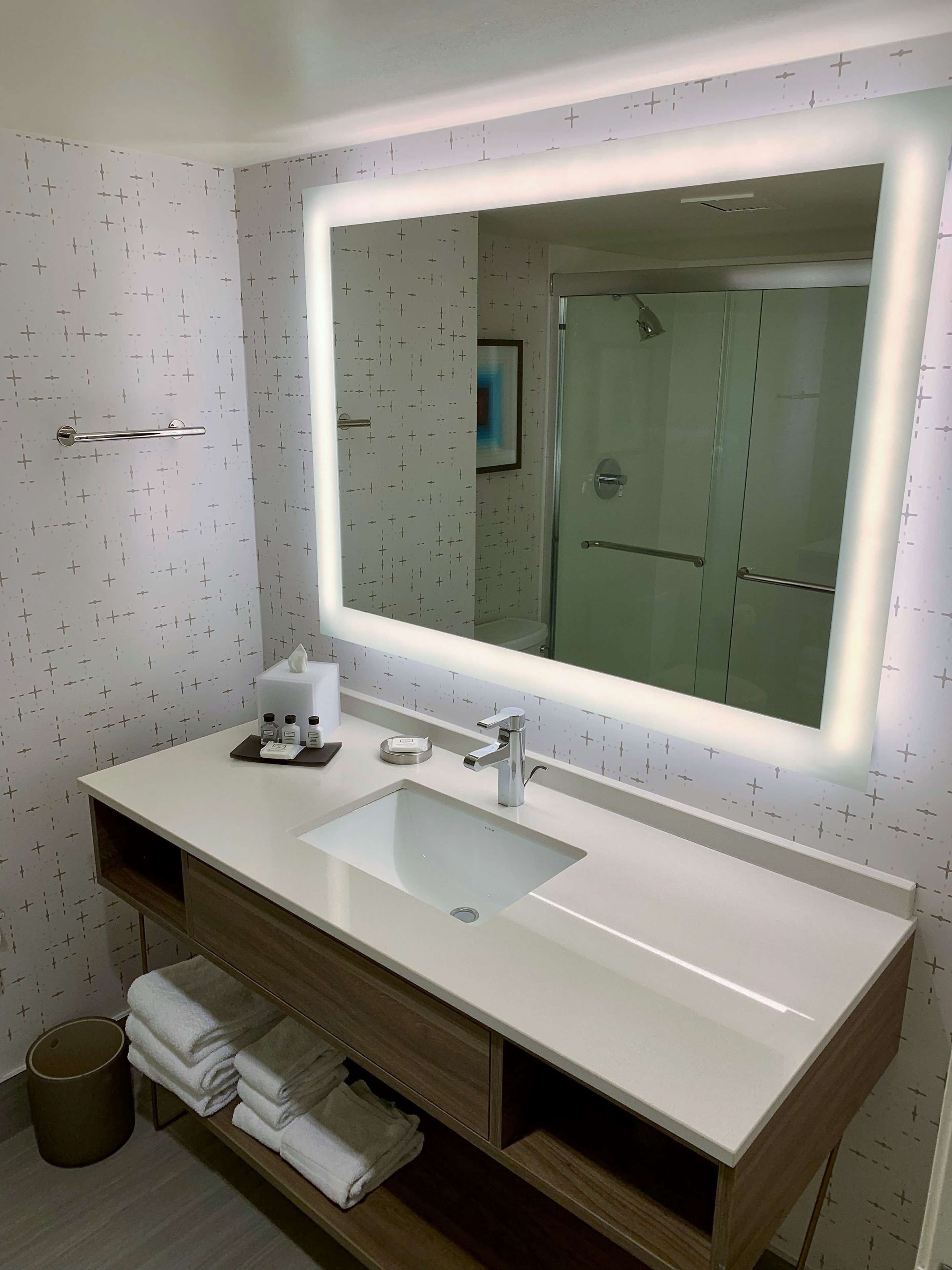 Un baño moderno con un espejo grande, lavamanos doble y tocador con espacio de almacenamiento.