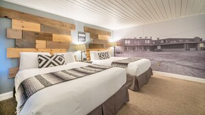 A bedroom with two beds, a wooden headboard, and a view of a building through a window. - Hotel Rapids (Grand Rapids)