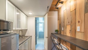 A modern kitchen with a stainless steel refrigerator, a sink, and wooden paneling on the walls. - Hotel Rapids (Grand Rapids)