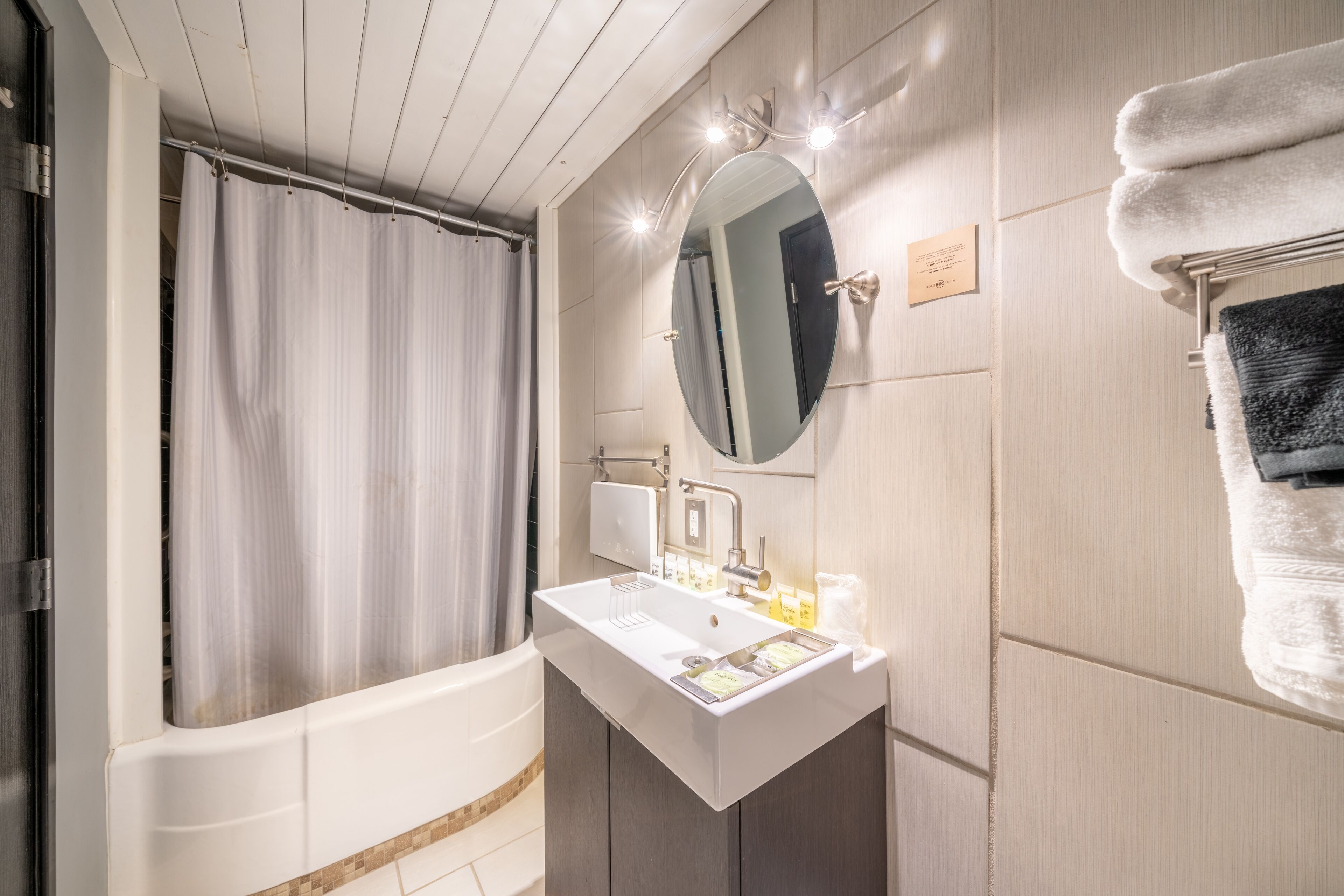 Et moderne badeværelse med badekar, et toiletbord med vask, et spejl og en bøjlestang til håndklæder.