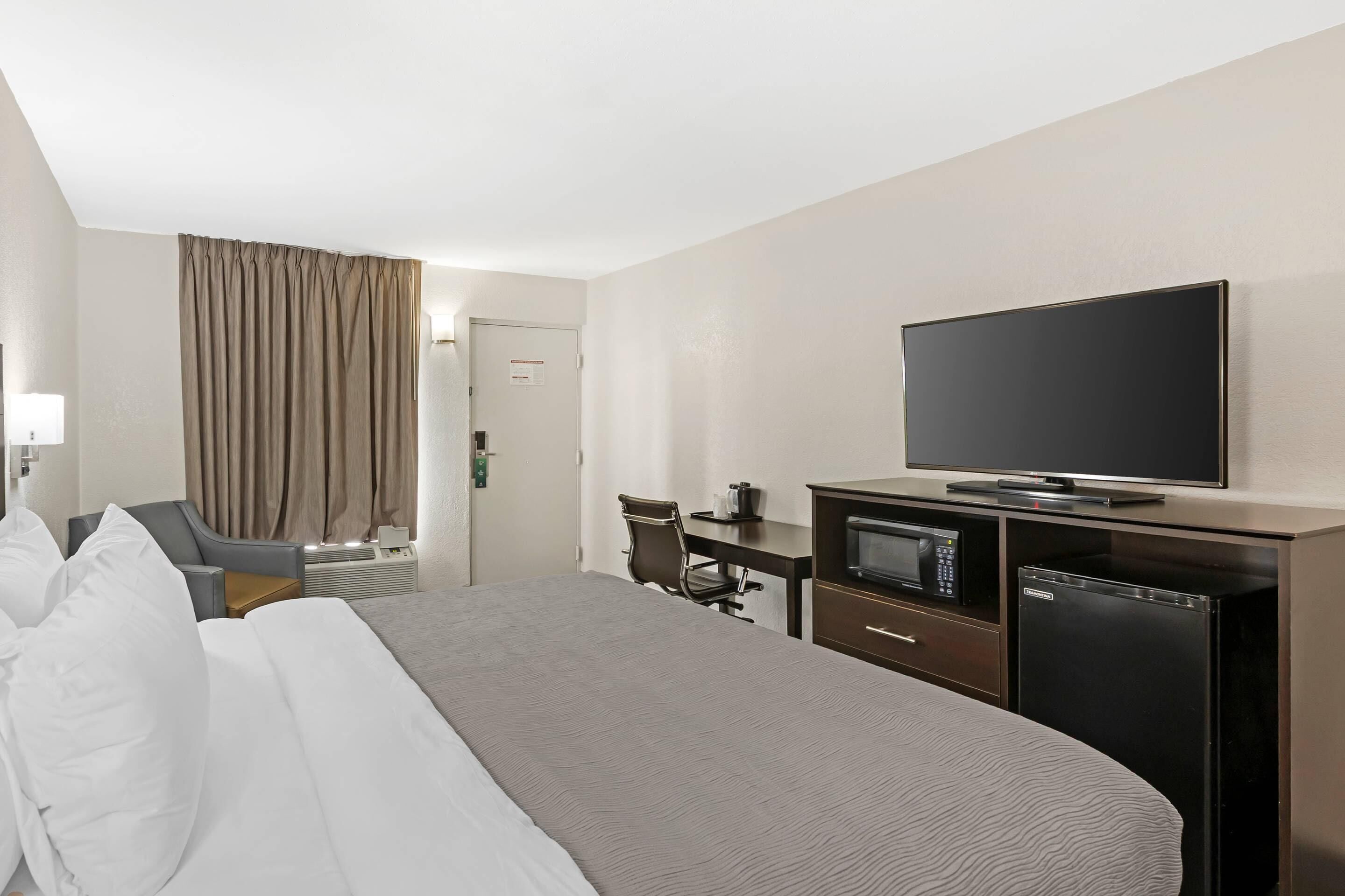 Une chambre d’hôtel équipée d’un lit, d’une télévision, d’un four à micro-ondes et d’un réfrigérateur.
