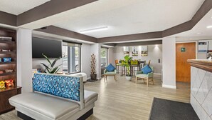 Un moderno vestíbulo de hotel con zona de estar, comedor y mostrador de recepción.