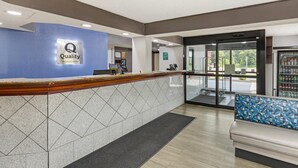 Zona de recepción de un hotel con una pared azul, un mostrador de recepción, un refrigerador de Gatorade y una sala de estar.