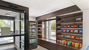 Máquina expendedora con Gatorade y otras bebidas, una sección de snacks con papas fritas y galletas, y vistas al exterior a través de una ventana.