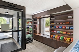 A vending machine stocked with Gatorade and other beverages, a snack display with chips and cookies, and a view of the outdoors through a window.