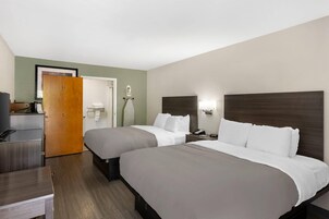 Habitación de hotel con dos camas, un escritorio, baño y televisión.