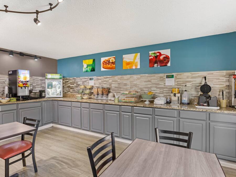 Une cuisine moderne avec des meubles gris, un plan de travail en granit et un bar pour prendre le petit-déjeuner. On y trouve divers appareils électroménagers, comme une machine à café, un four à micro-ondes et un appareil à gaufres.