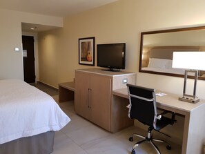 A hotel room with a bed, a desk with a chair, a television, a framed picture, and a mirror. - Hampton Inn by Hilton Monterrey-Airport (Apodaca)