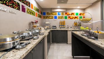 Una cocina moderna con encimera de granito, electrodomésticos de acero inoxidable y diversos alimentos.