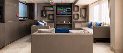 Una sala de estar moderna con un televisor de pantalla plana grande, asientos cómodos y una chimenea.