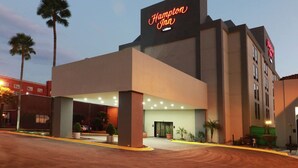 A Hampton Inn hotel with a modern facade, a prominent neon sign, and a well-lit entrance area. - Hampton Inn by Hilton Monterrey-Airport (Apodaca)