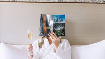 A person lying in bed with a book titled "New Orleans" and a glass of wine.