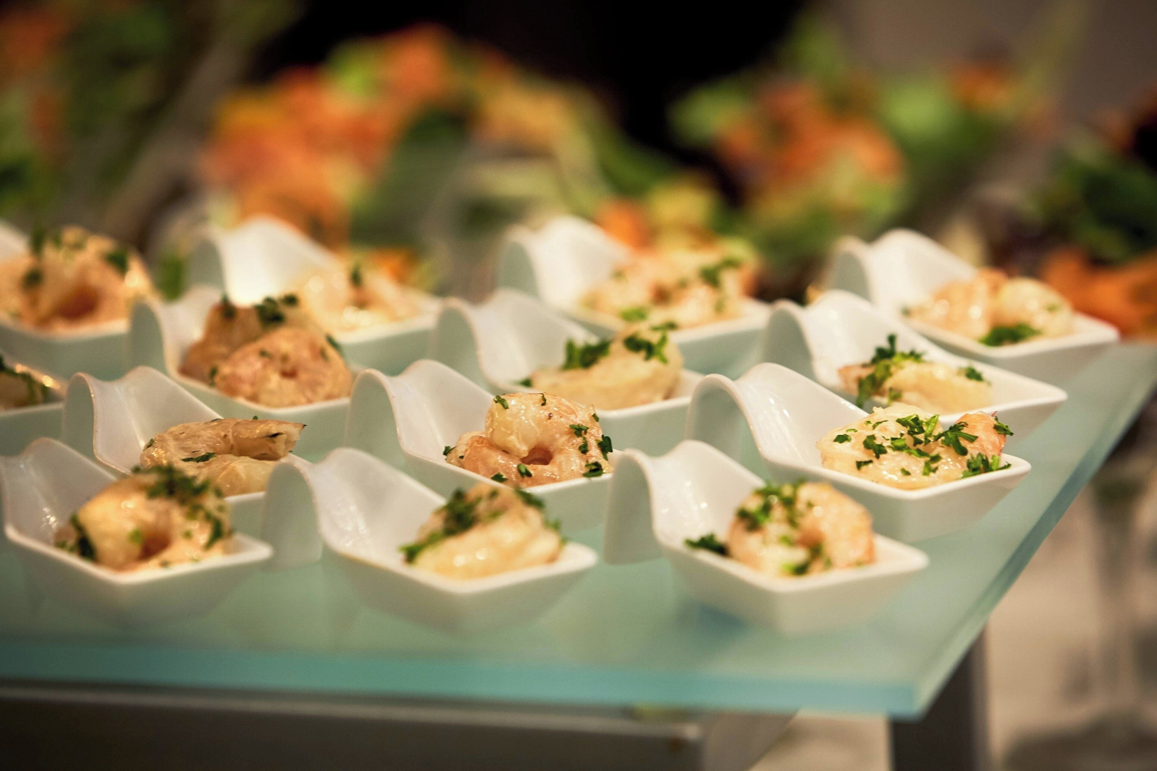 A glass table with neatly arranged food items in white bowls, garnished with herbs.