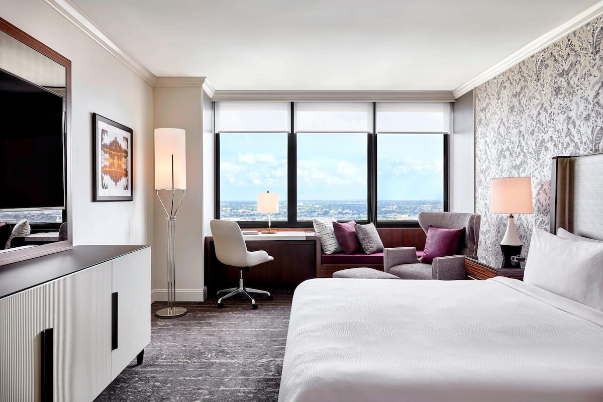 Une chambre d’hôtel avec un grand lit, un bureau avec une chaise, une télévision et une vue sur la ville.