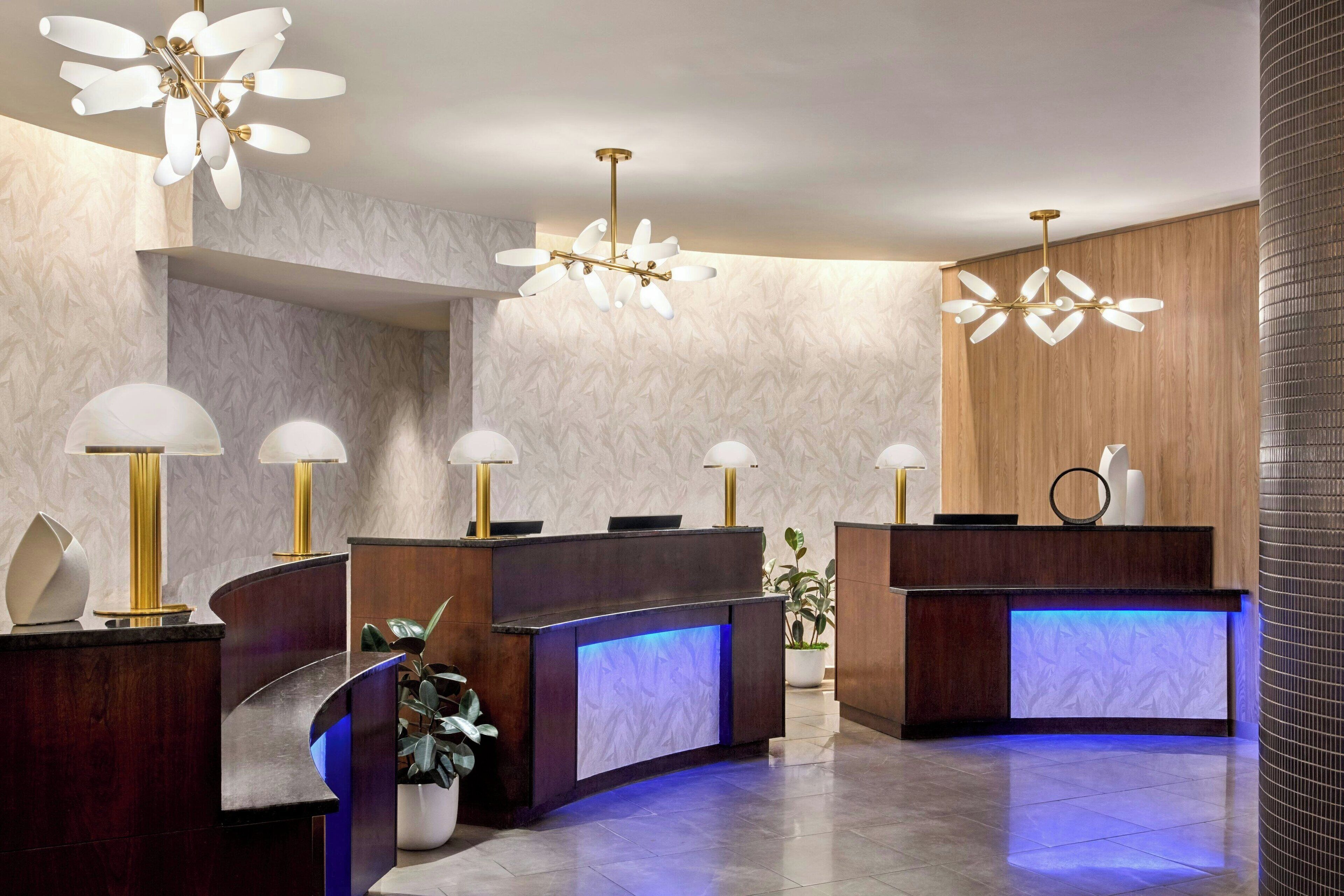 A reception area with a curved desk, two lamps, and a modern chandelier.