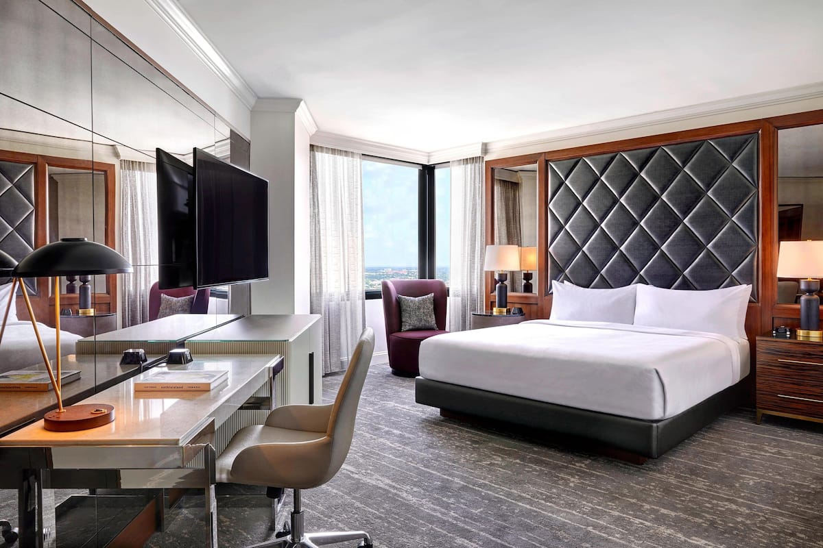 Une chambre d’hôtel avec un grand lit, un bureau avec une chaise, une télévision et une vue sur la ville.