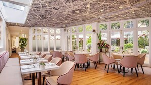 A spacious dining area with high ceilings and large windows, featuring multiple tables and chairs. - Renaissance Paris Nobel Tour Eiffel Hotel (Paris)