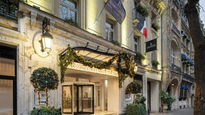 Une entrée imposante avec une porte en verre, une enseigne indiquant « Renaissance Paris », et un porche accueillant.