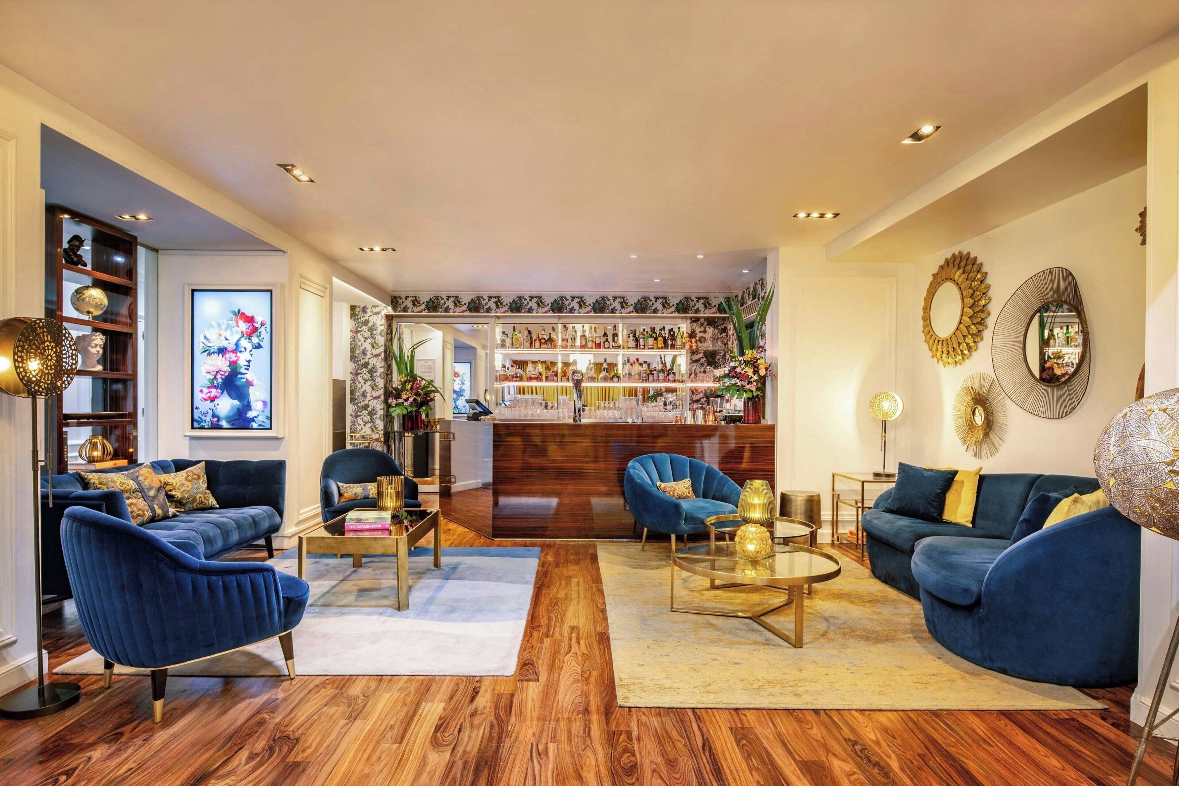 A modern living room with a bar area, featuring sofas, armchairs, and a coffee table.