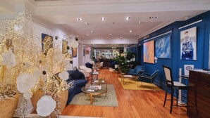 Un hall d’hôtel moderne avec un espace salon central, un comptoir d’accueil et des œuvres d’art accrochées aux murs.