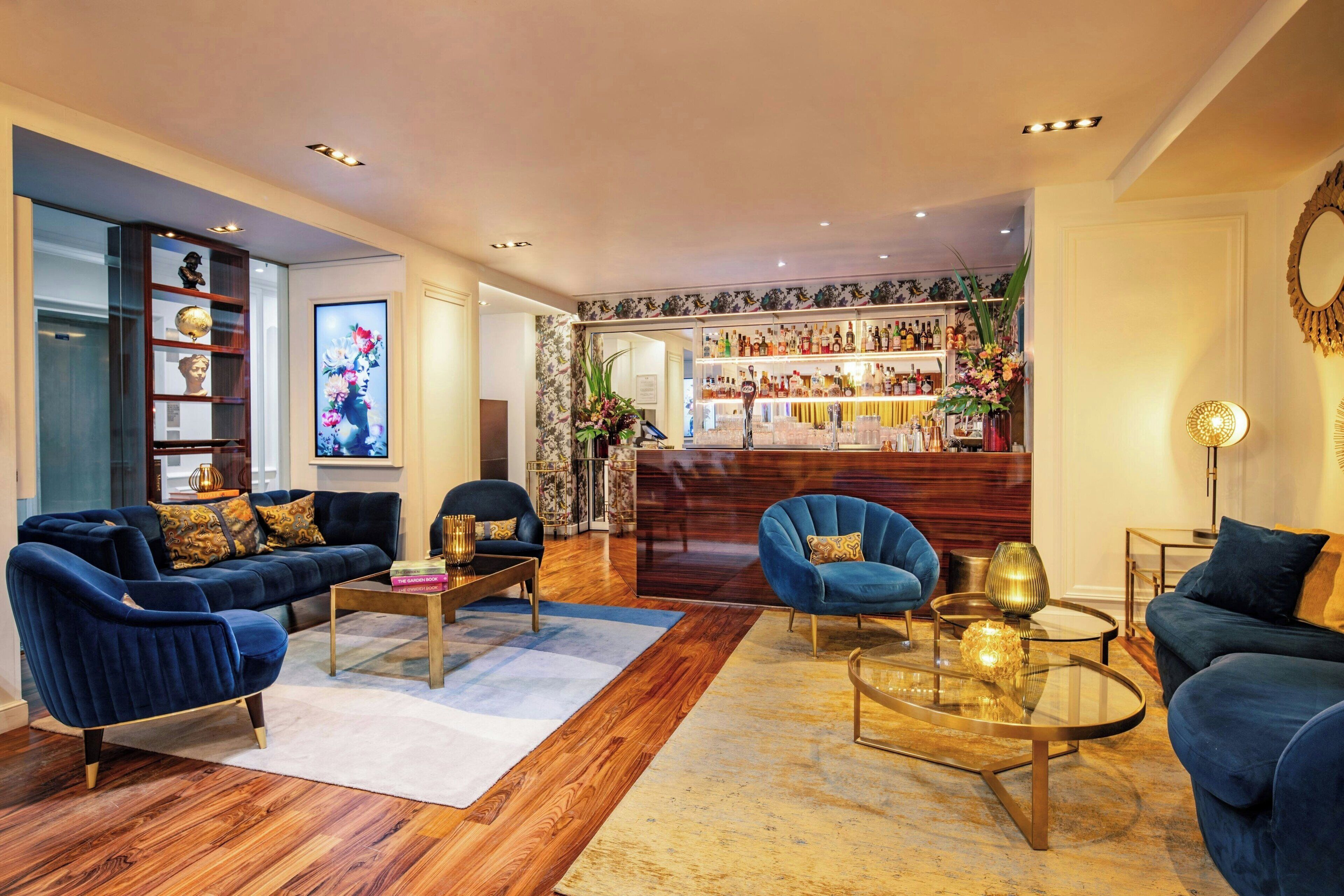 A modern living room with dark blue sofas, a glass coffee table, and a bar area with shelves of bottles and decorative items.