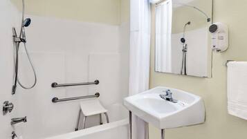 A modern bathroom with a bathtub, a sink, a handheld showerhead, a hairdryer, and a towel rack.